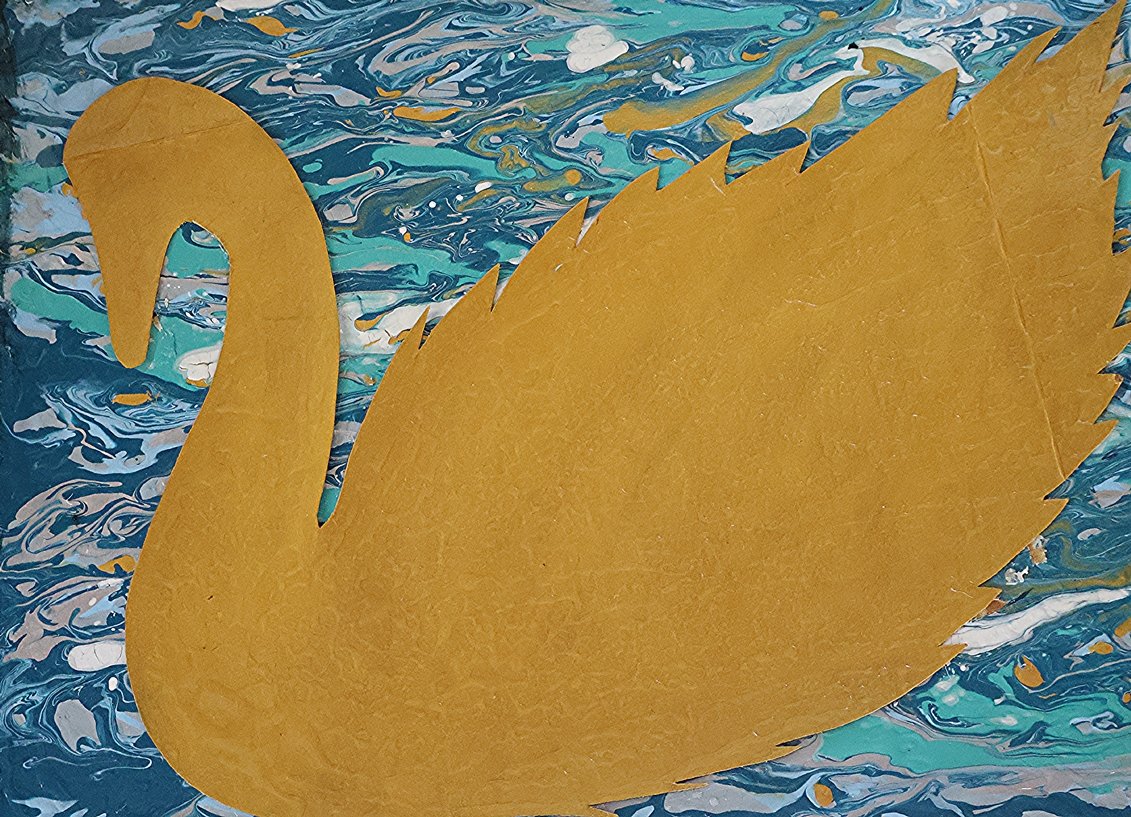 Gold-colored paper cutout of a swan placed on a marbled blue, white, and yellow background.