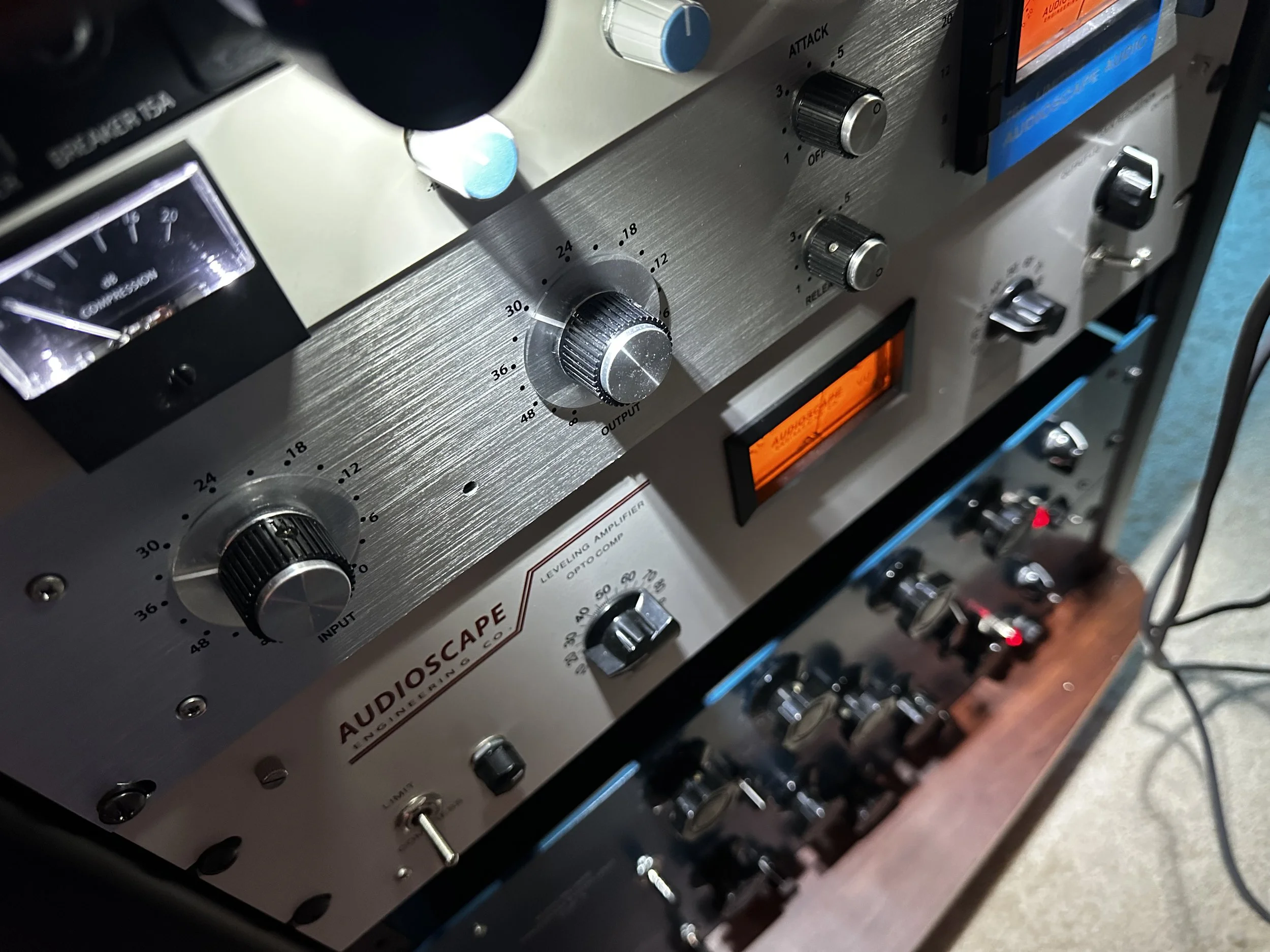 Close-up of an audio equipment rack with various knobs, switches, and meters, including a prominent volume knob, indicating it is a professional audio amplifier and equalizer system from Audioscape Inc.