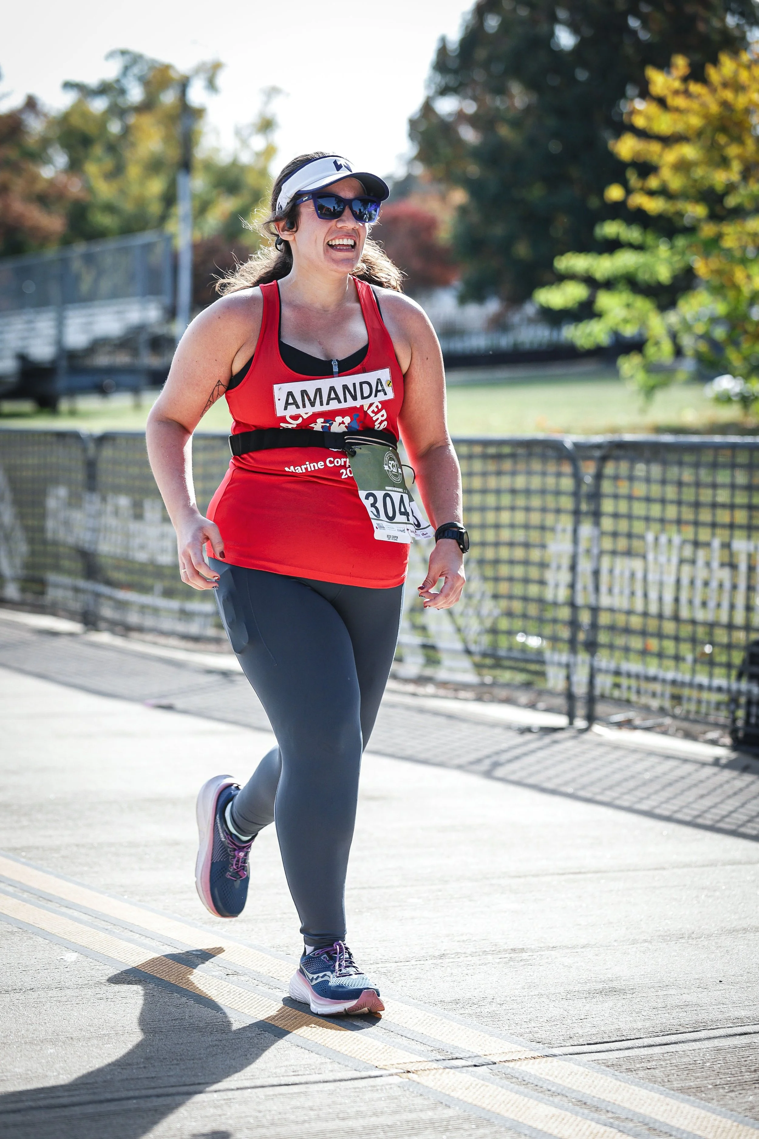 Amanda Kenney, LCSW smiling running marathon wearing red tank top and blue leggings
