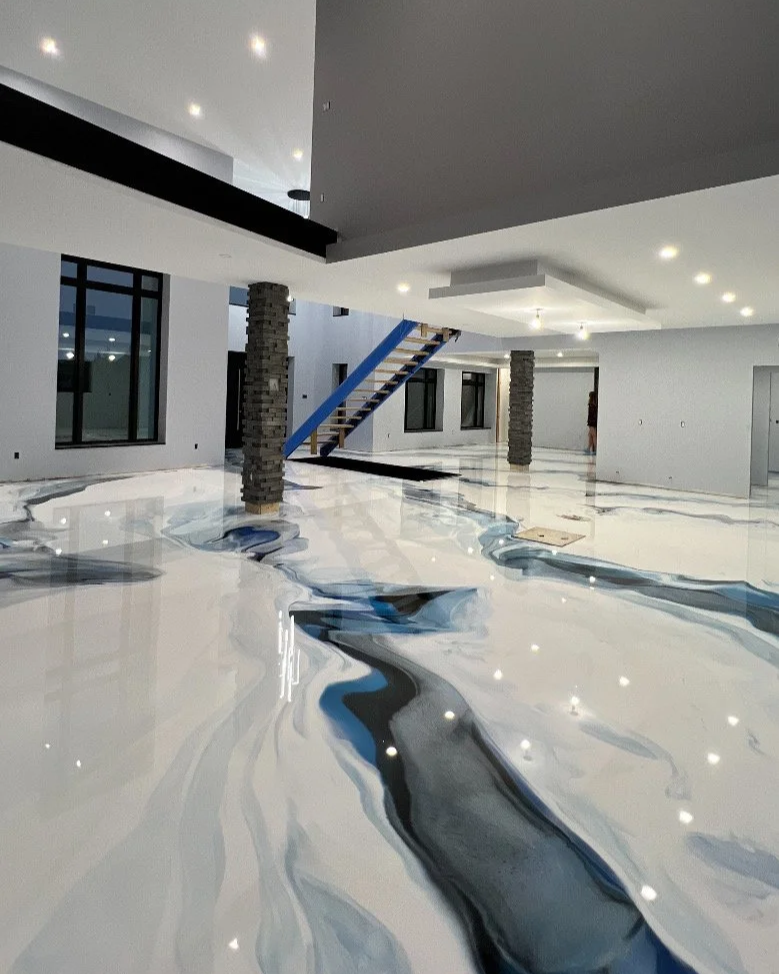 Interior of a modern building under construction with marble-like floor featuring black, blue, and gray veining, and unfinished stairway.