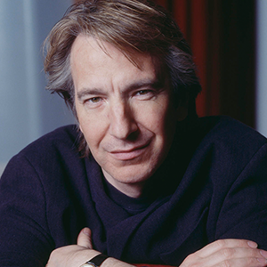 Close-up portrait of a middle-aged man with light brown hair, wearing a dark sweater, looking confidently at the camera with crossed arms.