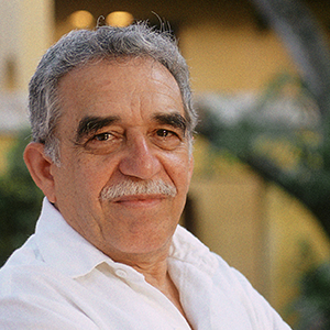 A middle-aged man with gray hair and a mustache, wearing a white shirt, standing outdoors with blurred greenery in the background.