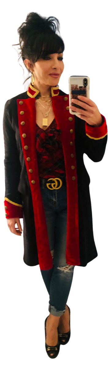 Woman taking a mirror selfie wearing a black and red coat with gold buttons and trim, distressed jeans, black heels, and gold jewelry.