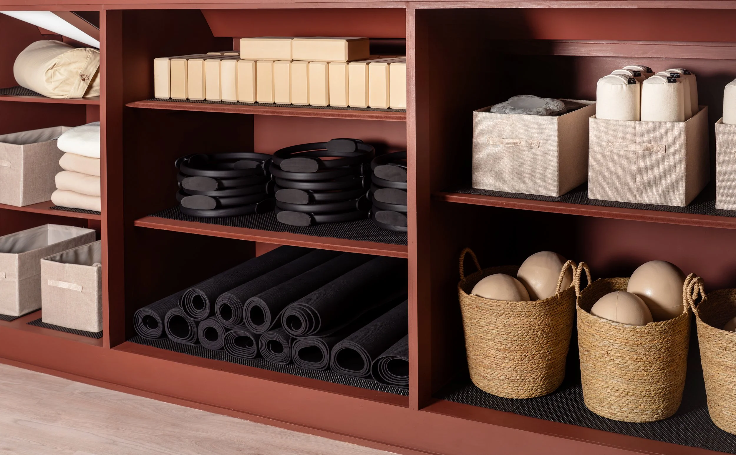 Shelves with neatly organized workout gear including foam rollers, yoga mats, resistance bands, kettlebells, and storage bins.