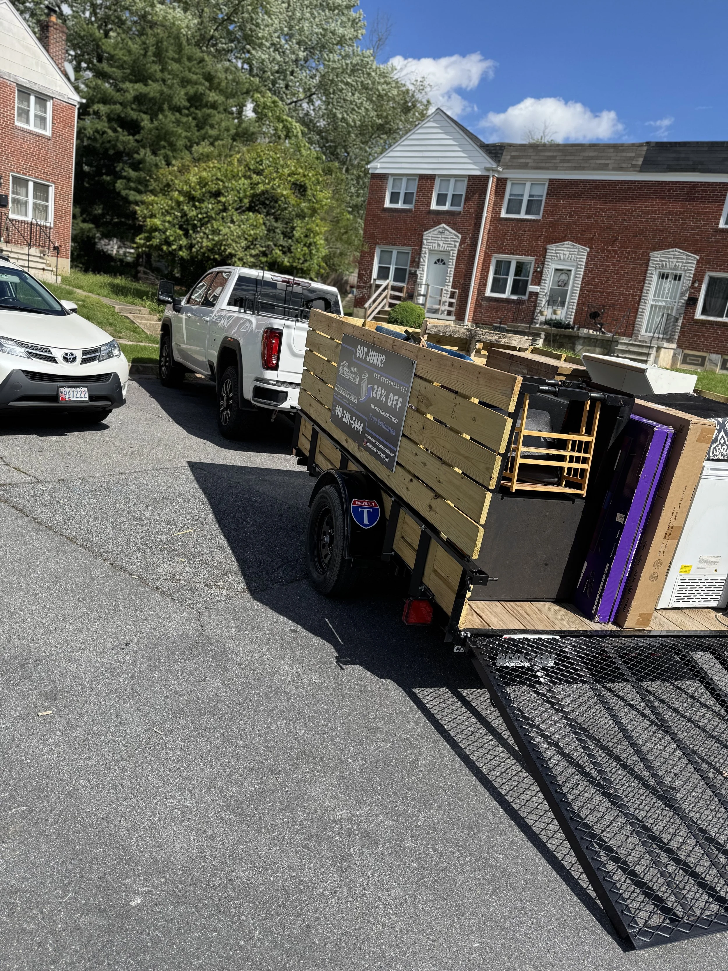 A trailer filled with furniture and household items parked in front of residential buildings on a sunny day.