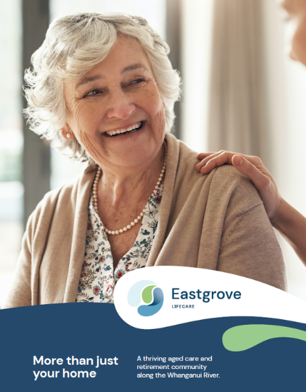 An elderly woman smiling and being comforted by a person resting their hand on her shoulder, with a brochure from Eastgrove Lifecare in the foreground.