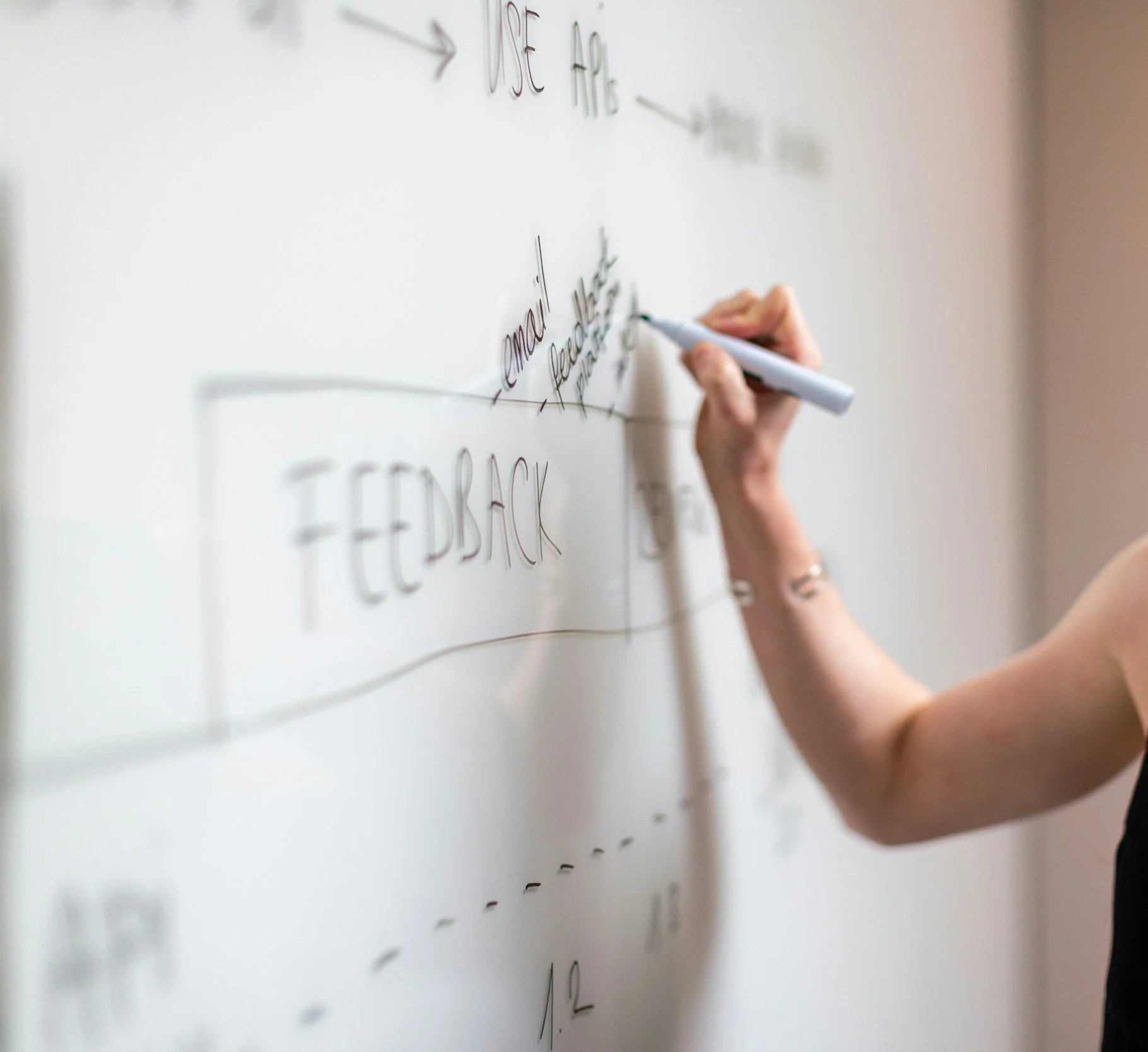 Person writing on a whiteboard, illustrating collaborative design of evidence-informed, accessible mental health programs.