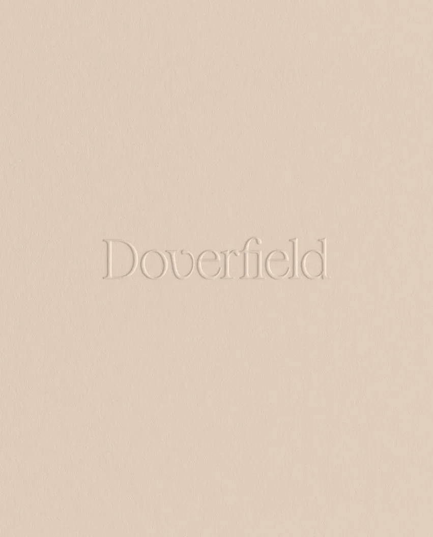 Close up of the brand name debossed into heavy cream cardstock creating a subtle texture-rich architectural effect