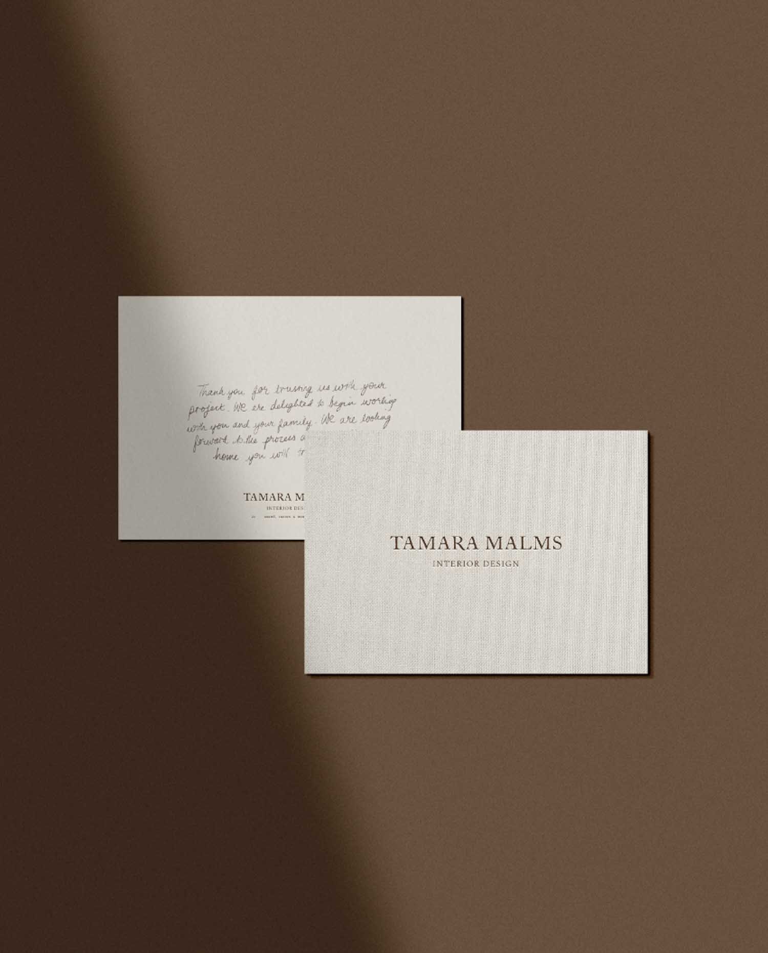 Two cards on a brown background including a handwritten thank you note and a Tamara Malms Interior Design business card
