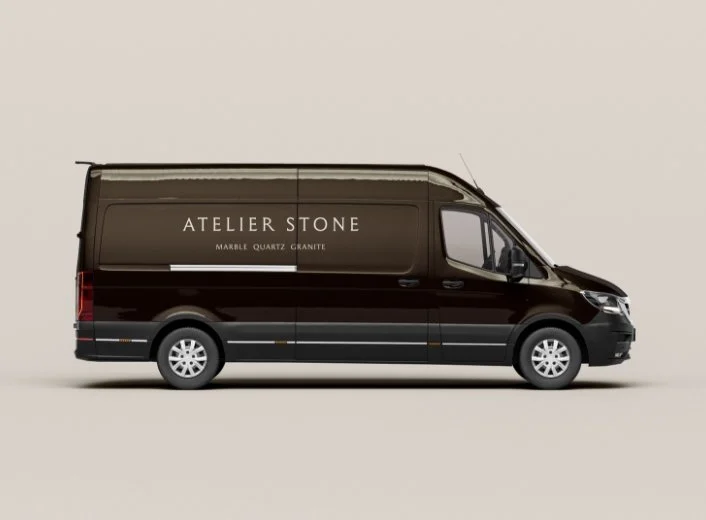 Side view of a luxury dark brown van featuring the Atelier Stone logo and Marble Quartz Granite text in a serif font