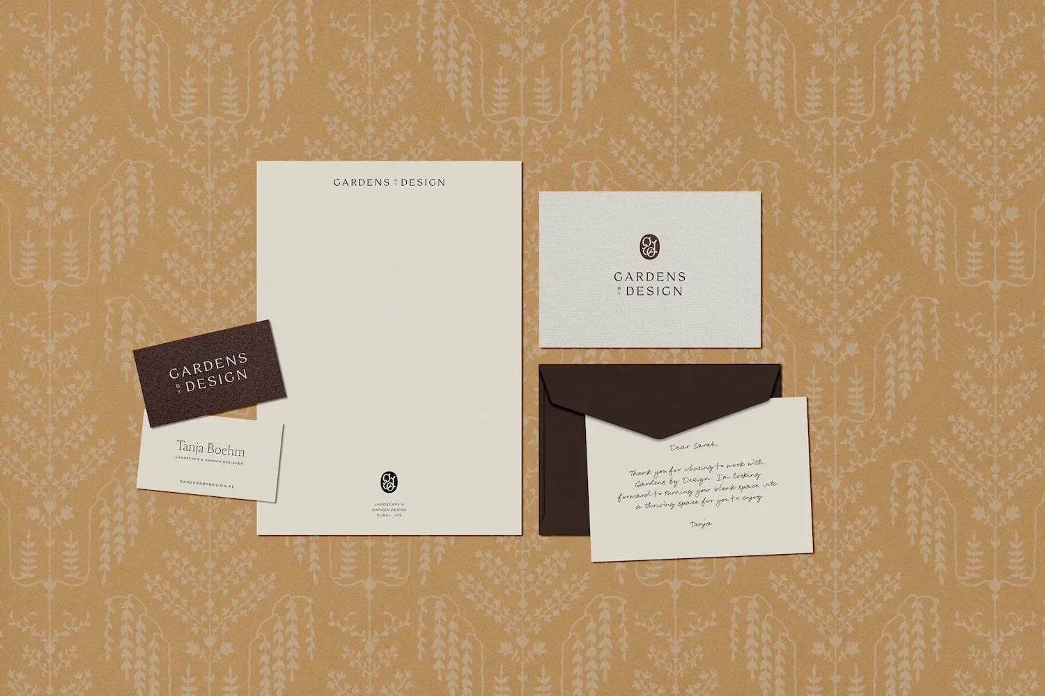 Flat lay of Gardens by Design brand stationery including letterhead, business cards, branded envelope and written card