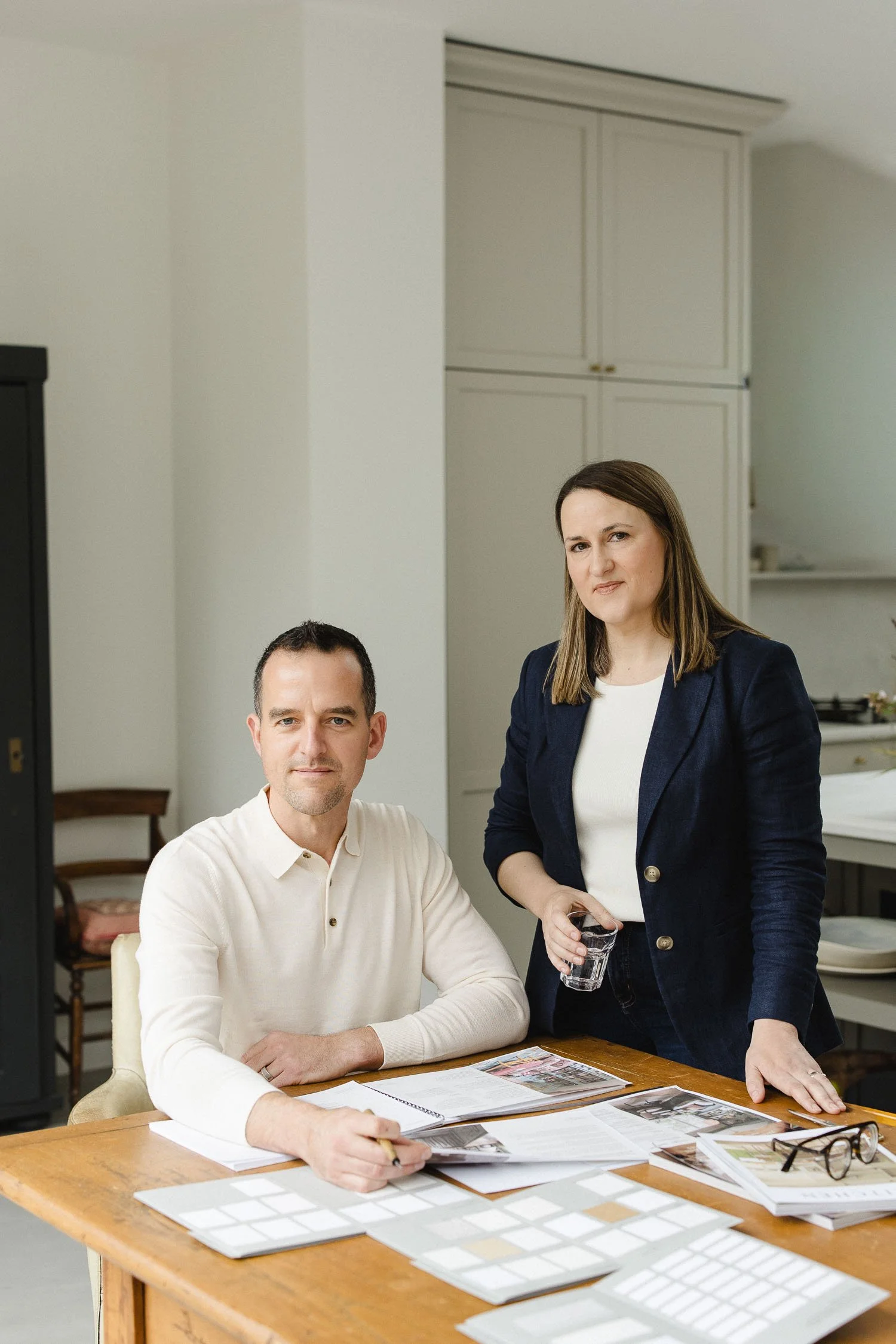Portrait of Wildings Studio creative directors sitting at a wooden desk with brand strategy documents and colour swatches