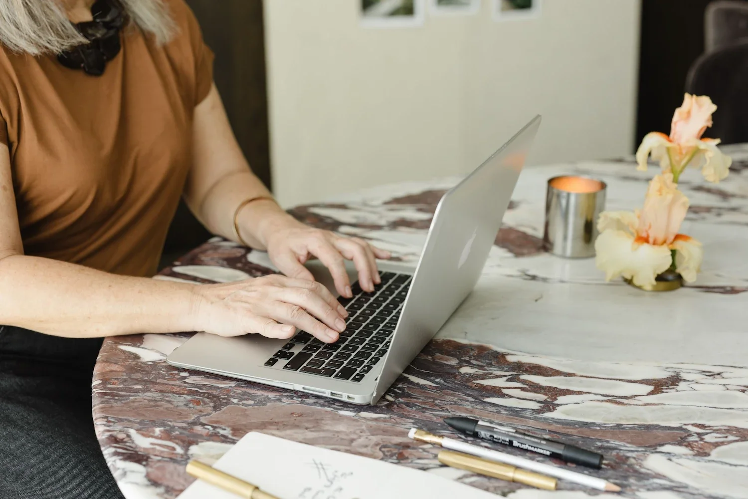 Garden designer working on a laptop at a marble table inside a studio to build a strong brand identity