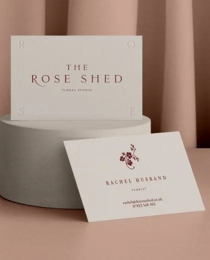 Two elegant business cards for a florist featuring dark red serif text and a floral logo on a textured cream cardstock