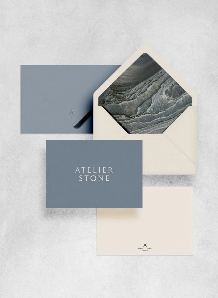 Atelier Stone stationery including a blue business card cream envelopes and a liner showing grey marble stone patterns