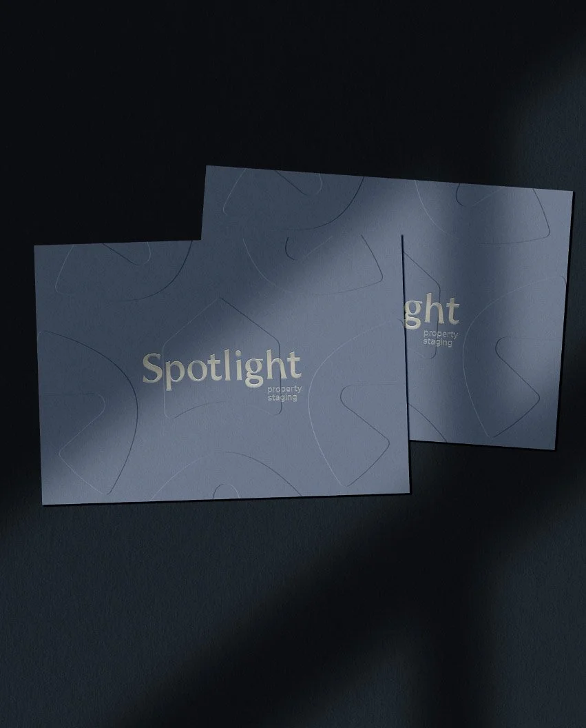 Two blue brand cards for Spotlight property staging with gold foil lettering and embossed geometric patterns under sunlight