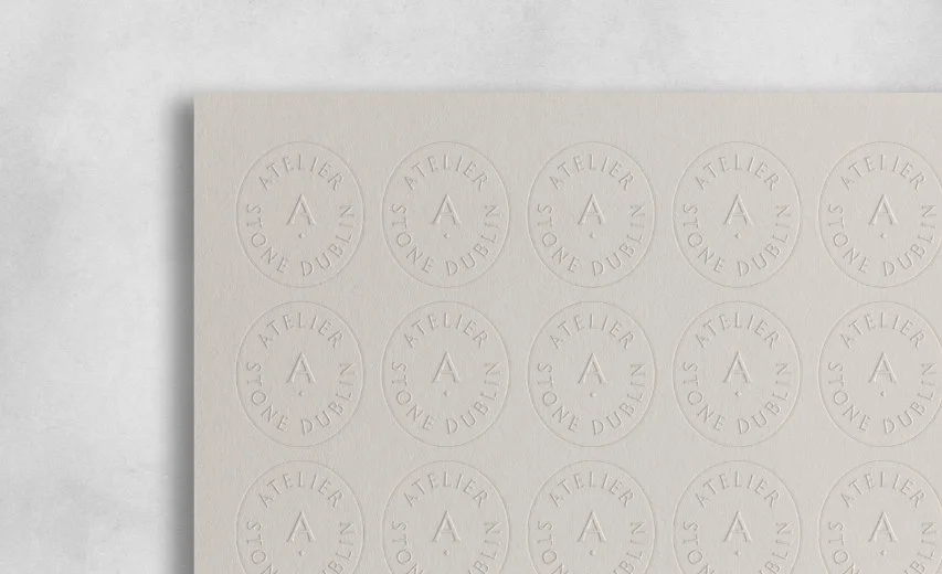 Sheet of circular cream stickers with a debossed brand logo featuring the letter A and Stone Dublin text on grey paper