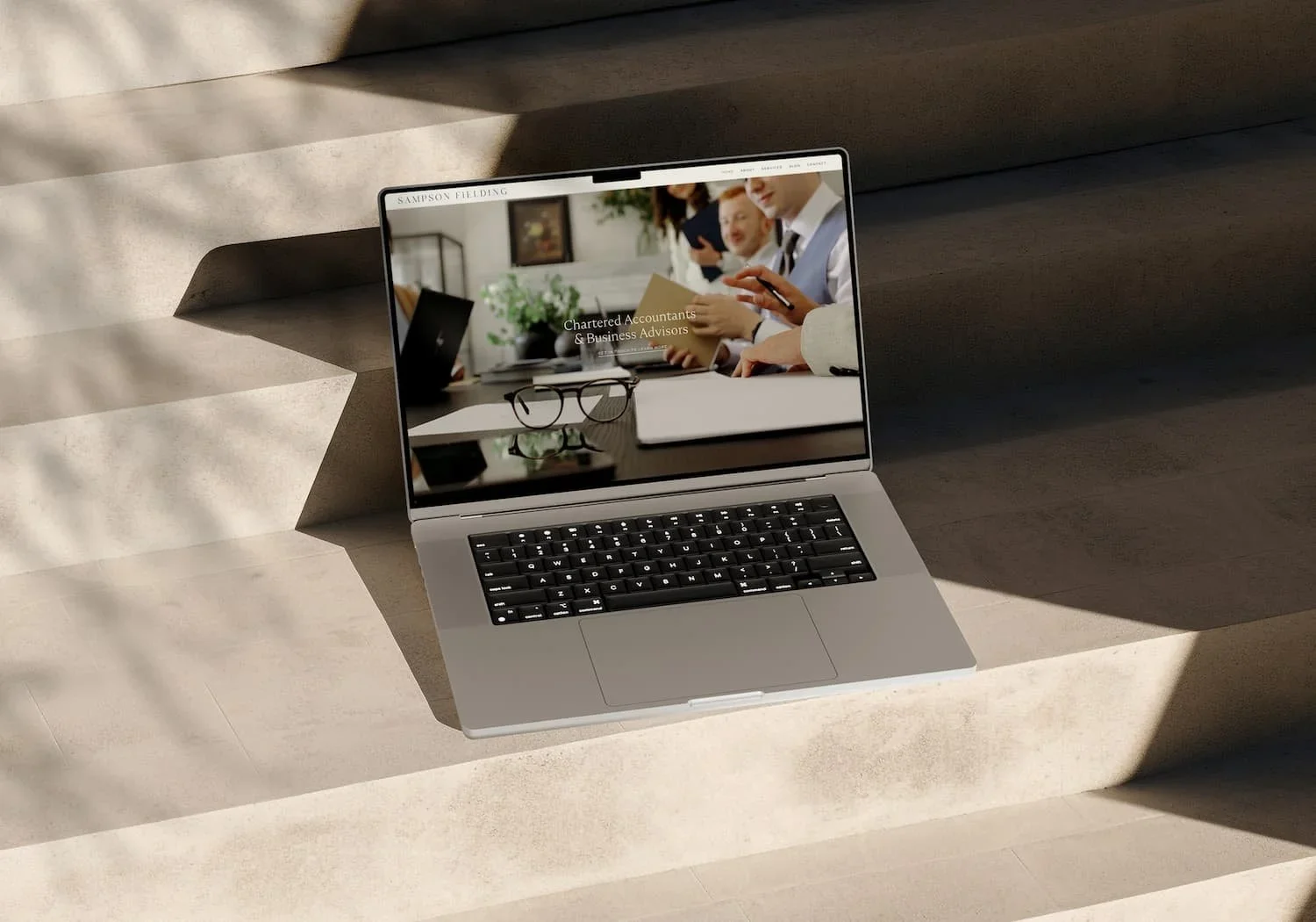 Laptop on concrete stairs displaying Sampson Fielding website for chartered accountants plus business advisors hero image