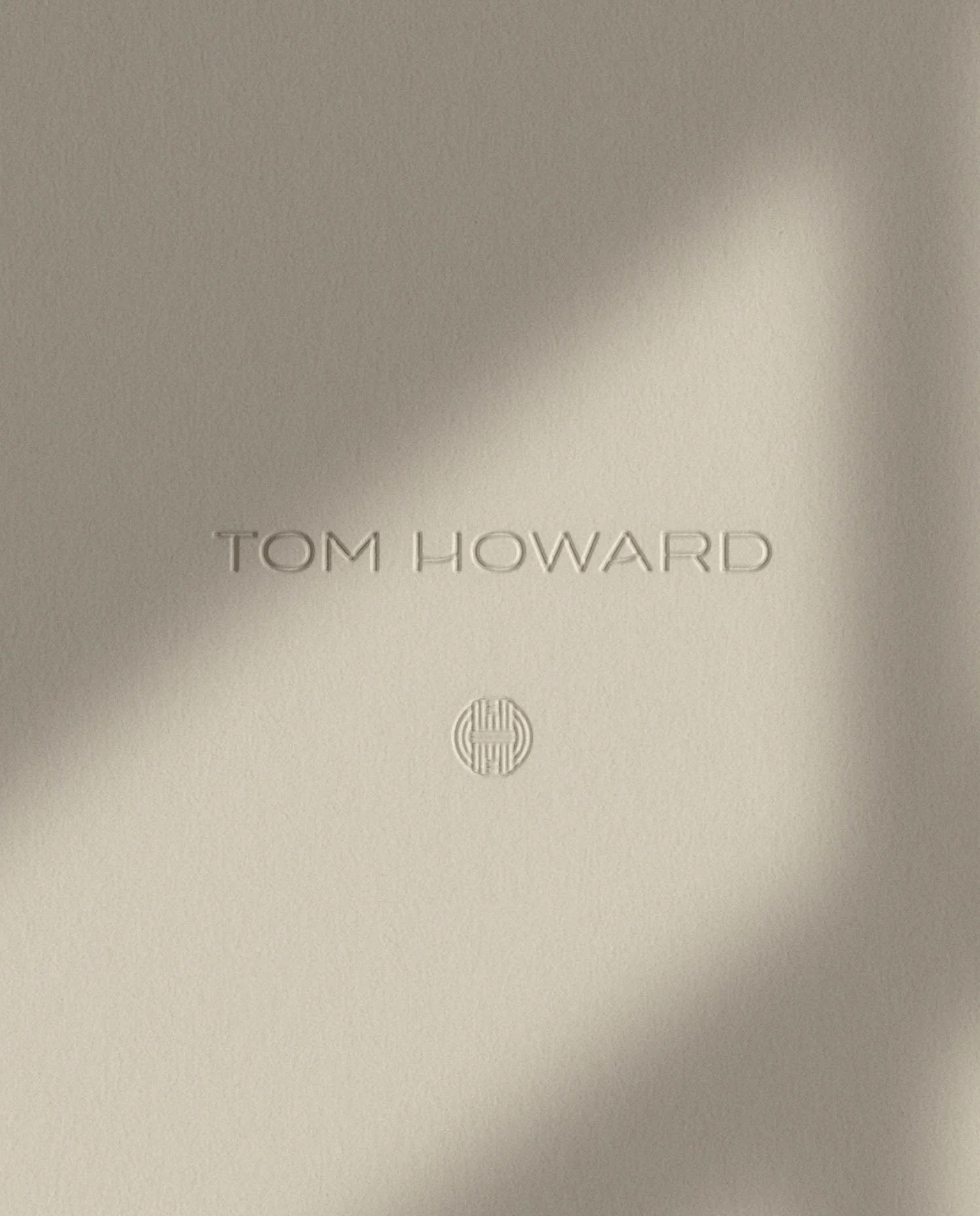 Minimalist branding showing the name Tom Howard and a circular geometric icon embossed into thick premium textured paper