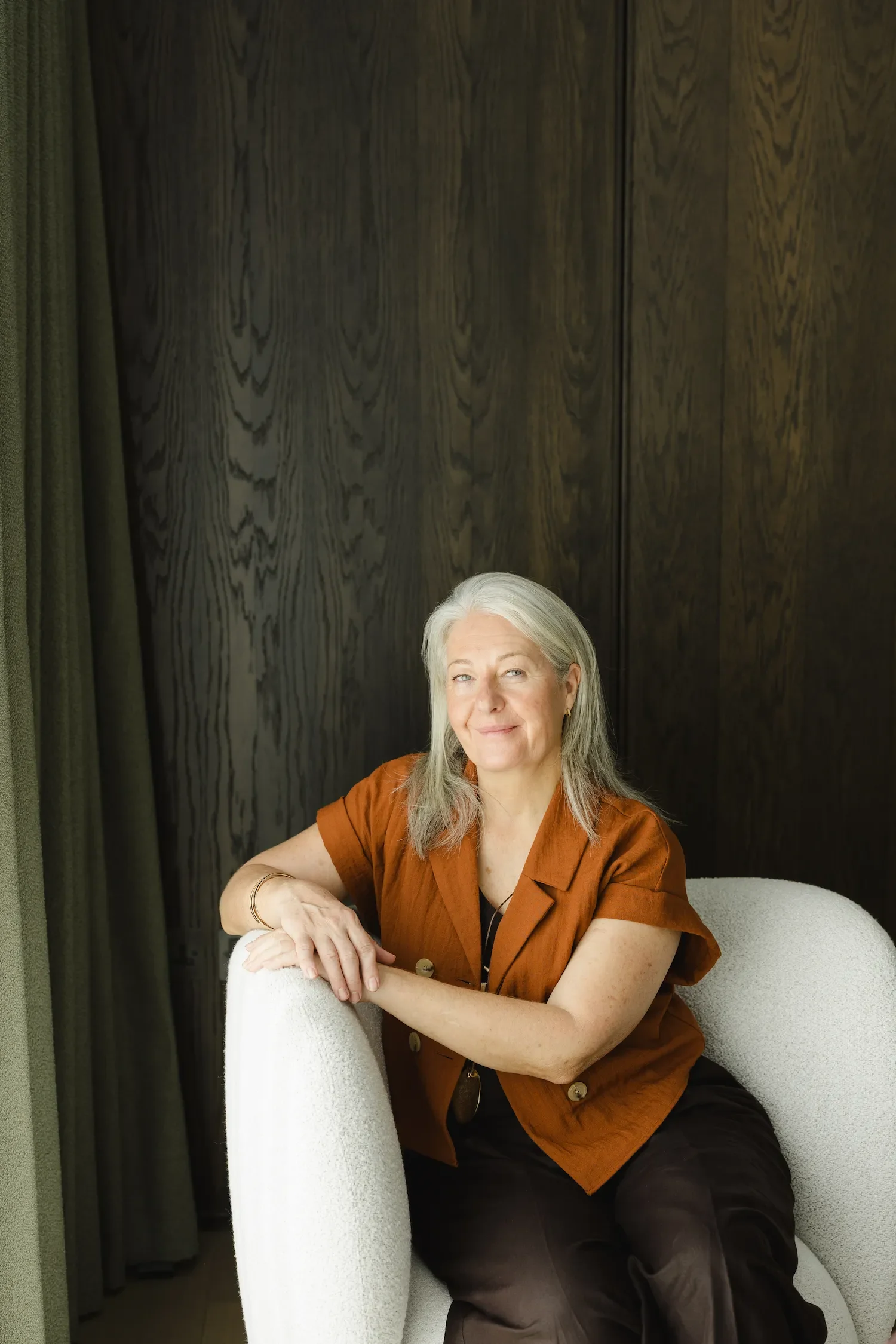 Tanja Boehm sitting comfortably in a white armchair smiling in her modern Dubai garden design studio
