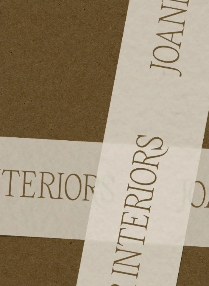 Translucent white branding tape with brown serif text layered over a textured brown recycled cardboard packaging box