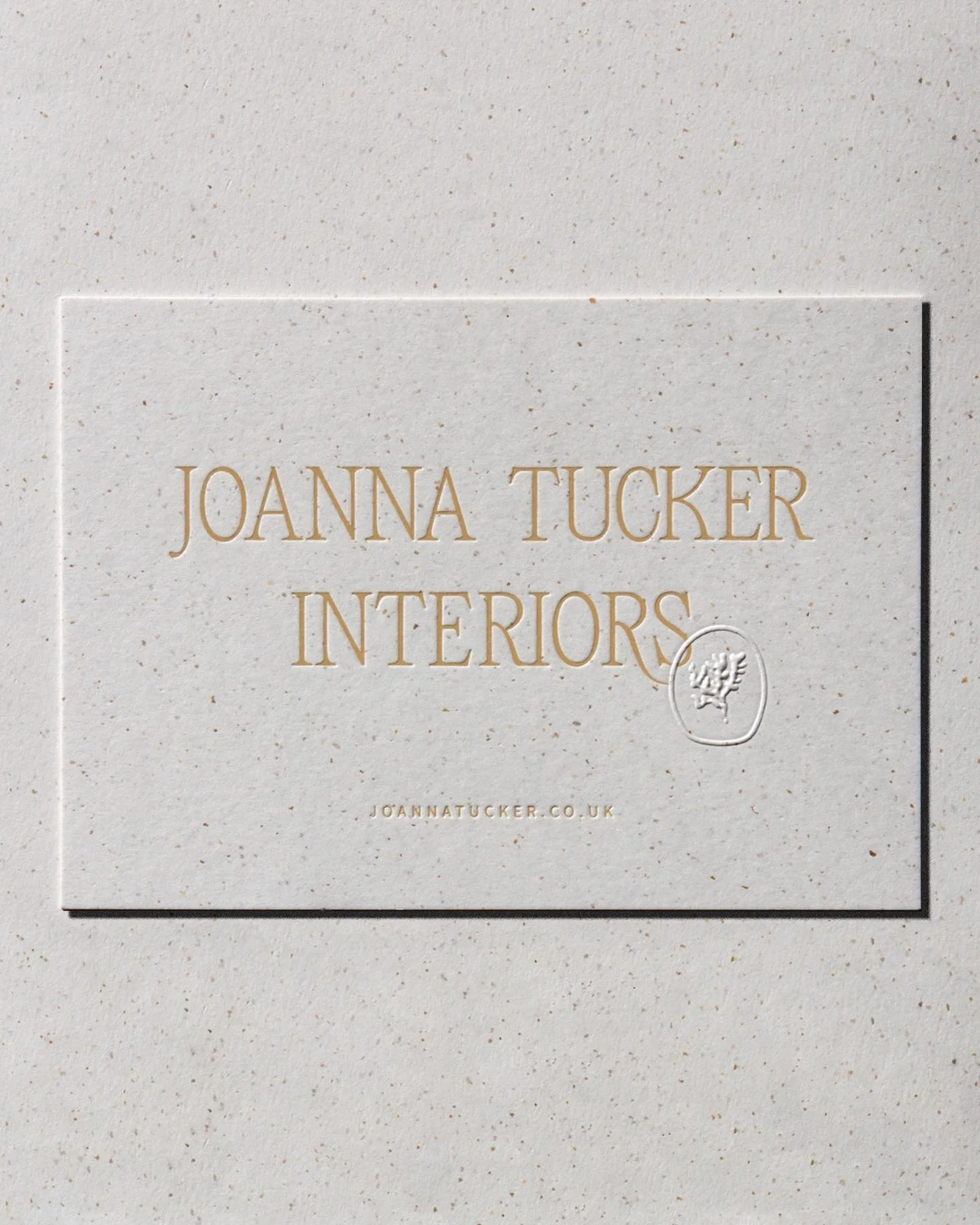 Business card with Joanna Tucker Interiors & website lettering in gold foil blocking on fleckled off-white recycled cardstock