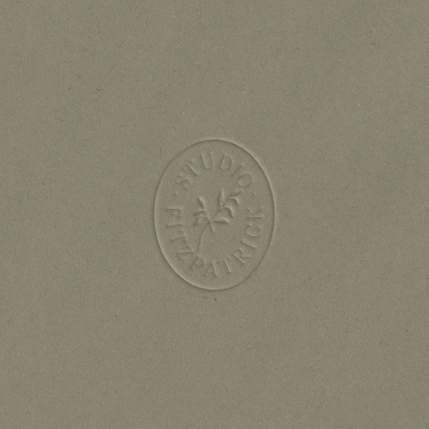 Circular blind embossed logo sticker showing a delicate leafy branch on premium textured khaki card stock packaging