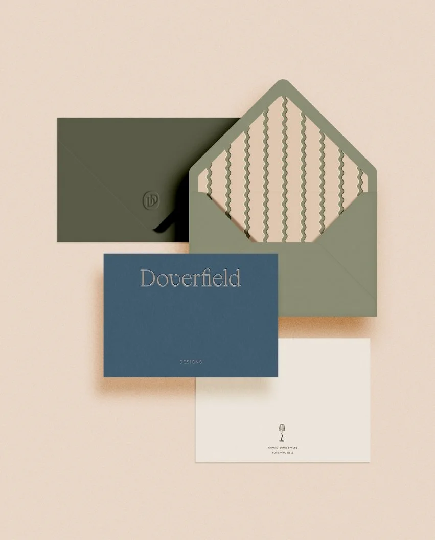 Set of envelopes and cards in forest green blue and cream featuring a wavy pattern liner and a lamp icon at the bottom