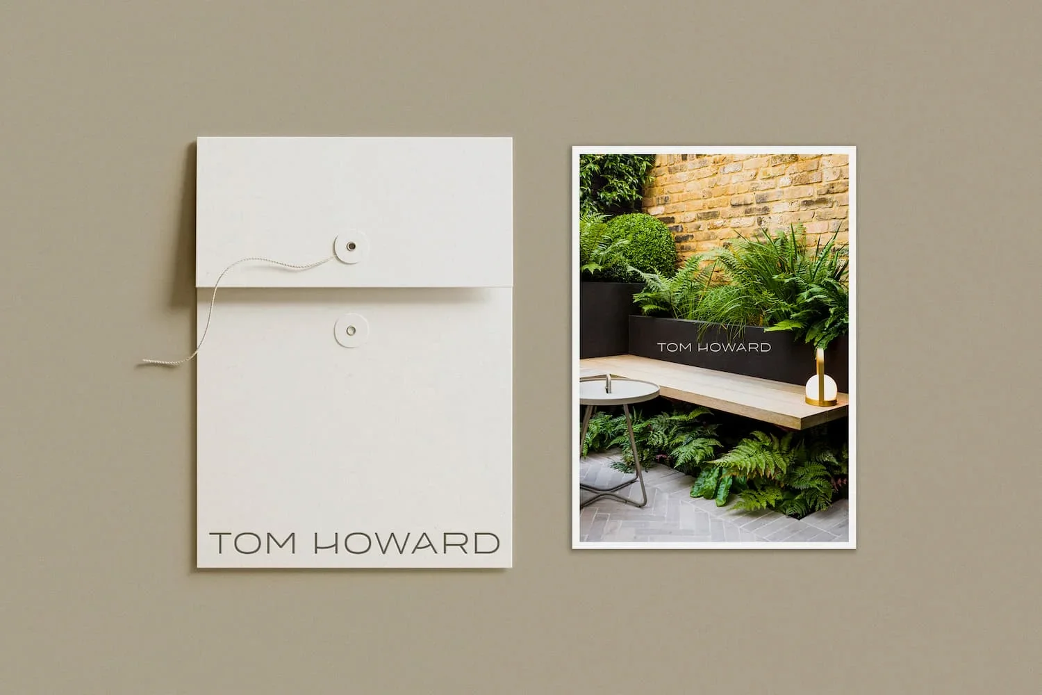 Tom Howard garden design stationery with white string tie envelope next to a postcard of a lush walled garden with ferns