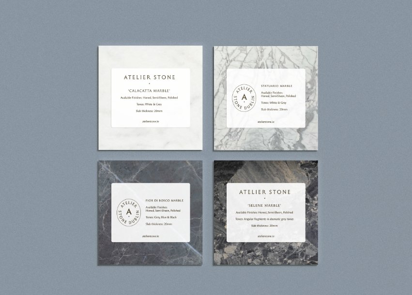 Four square marble samples including Calacatta and Statuario with informative white brand labels on a blue background