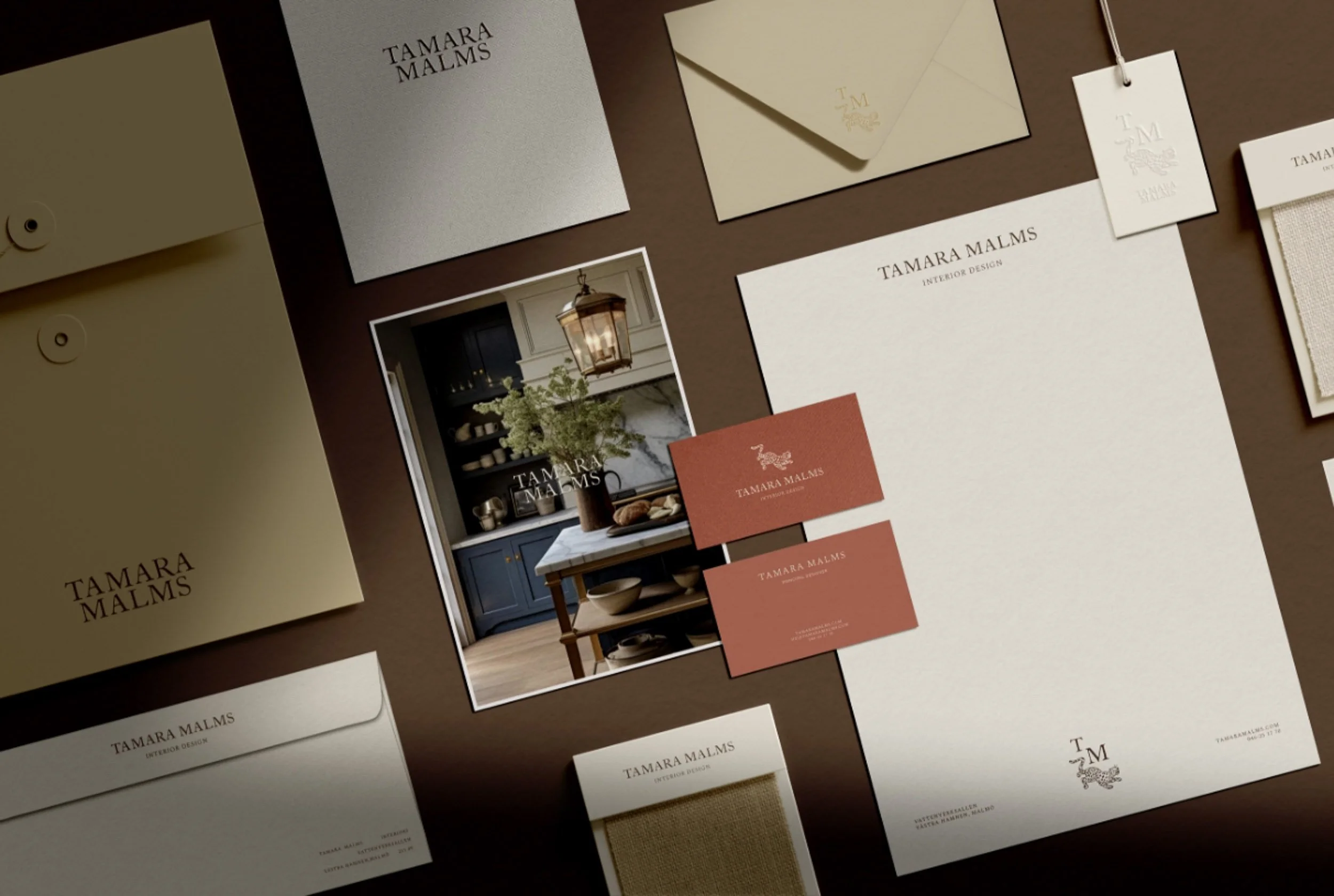 Tamara Malms interior design stationery set with business cards envelopes and a photo of a kitchen on a brown background