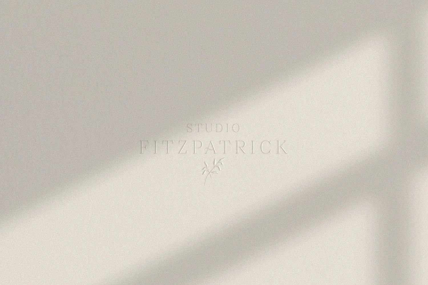Refined serif brand name elegantly debossed on minimalist off white textured paper with soft geometric shadows