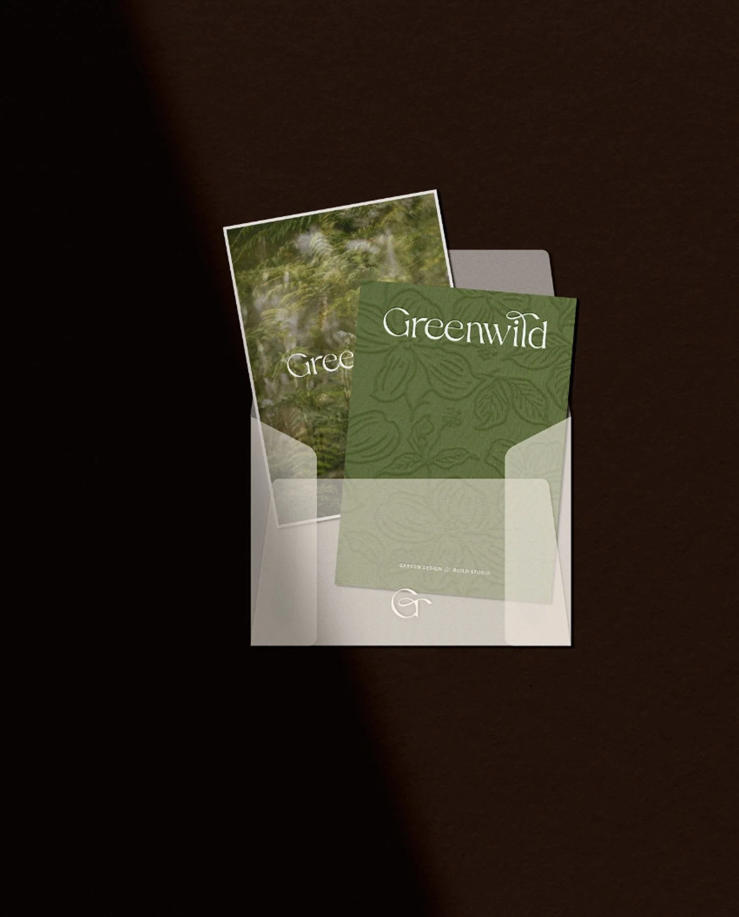 Translucent vellum envelope holding a Greenwild floral brand card and a high-resolution photograph of a lush garden