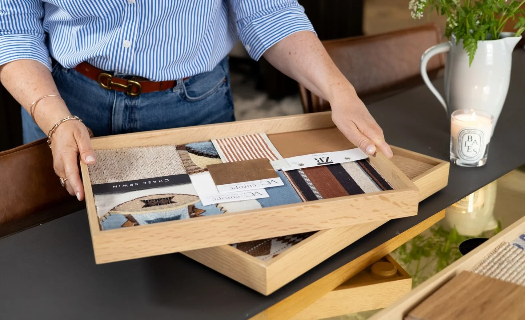Interior designer holding a light oak tray containing various fabric swatches, striped patterns and textile samples