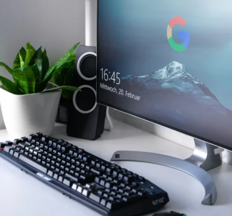 Desktop setup with a mechanical keyboard and a monitor showing a Google logo over a snowy mountain peak at 16:45