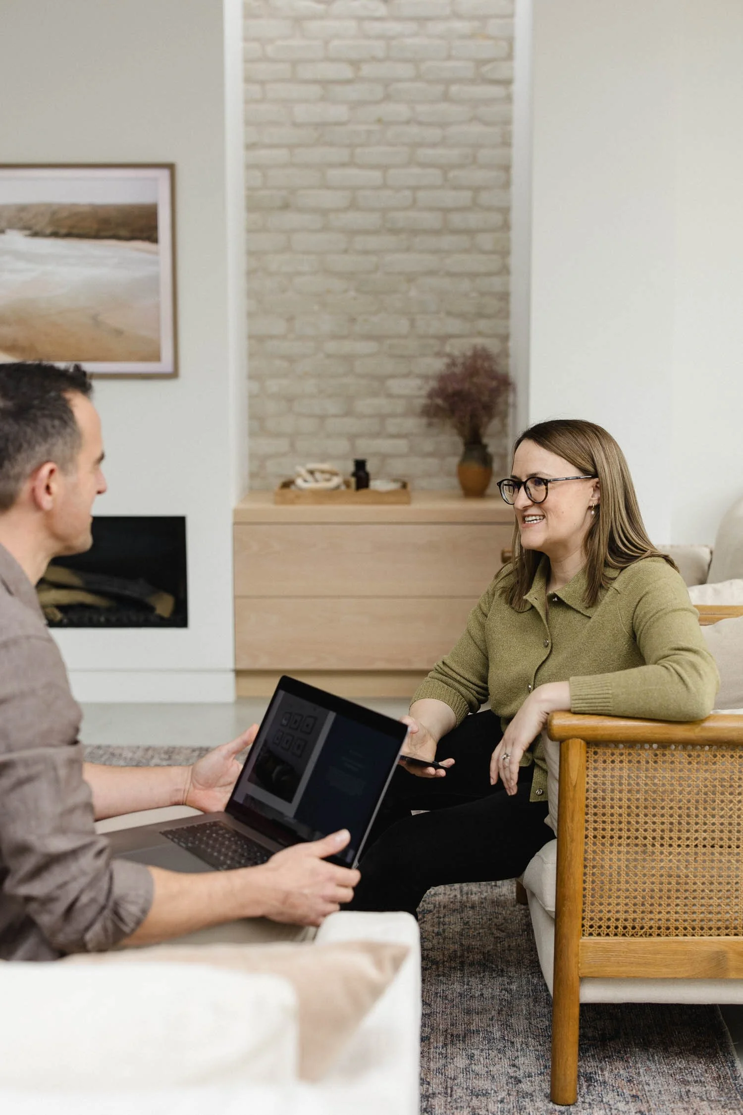Two creative professionals sitting in a bright studio discussing website layouts on a laptop and mobile phone together
