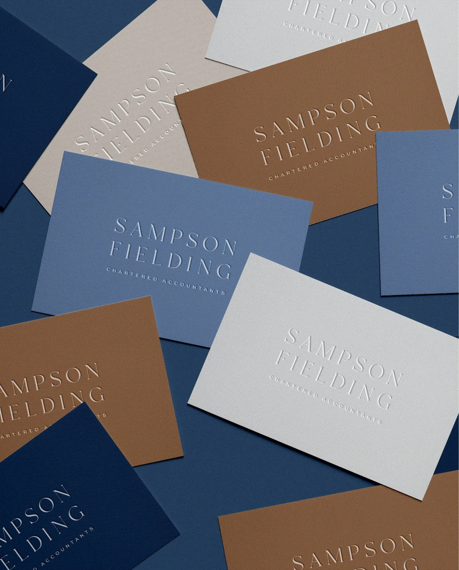 A variety of Sampson Fielding business cards in navy blue, light blue, caramel and ivory with elegant embossed typography