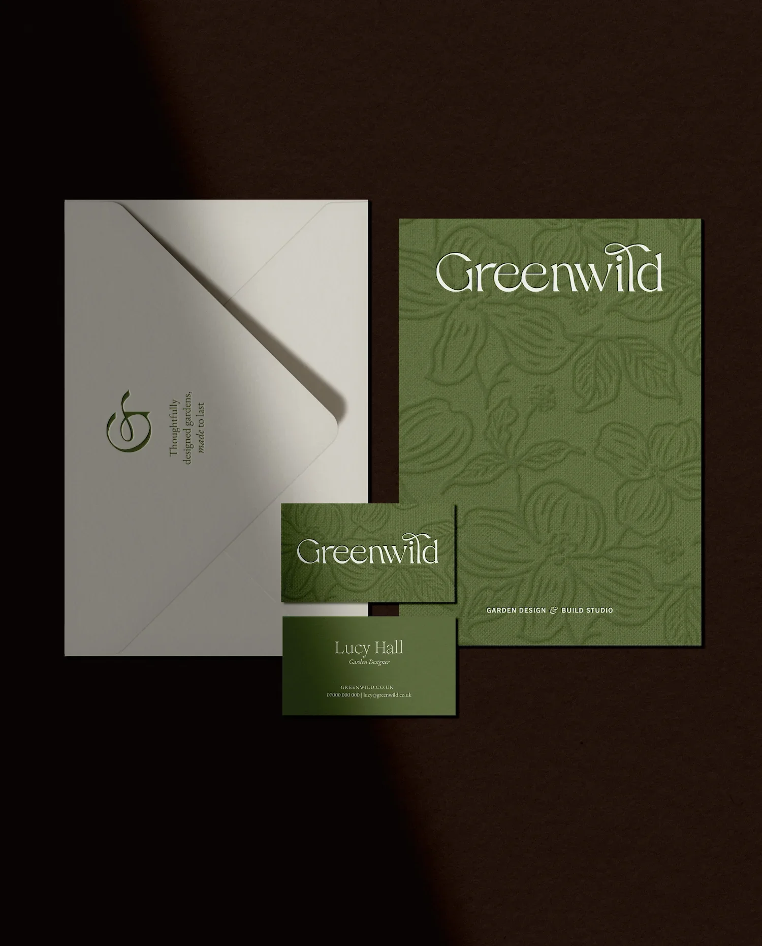 Greenwild brand stationery set including a debossed floral folder and a cream envelope with a minimalist green logo
