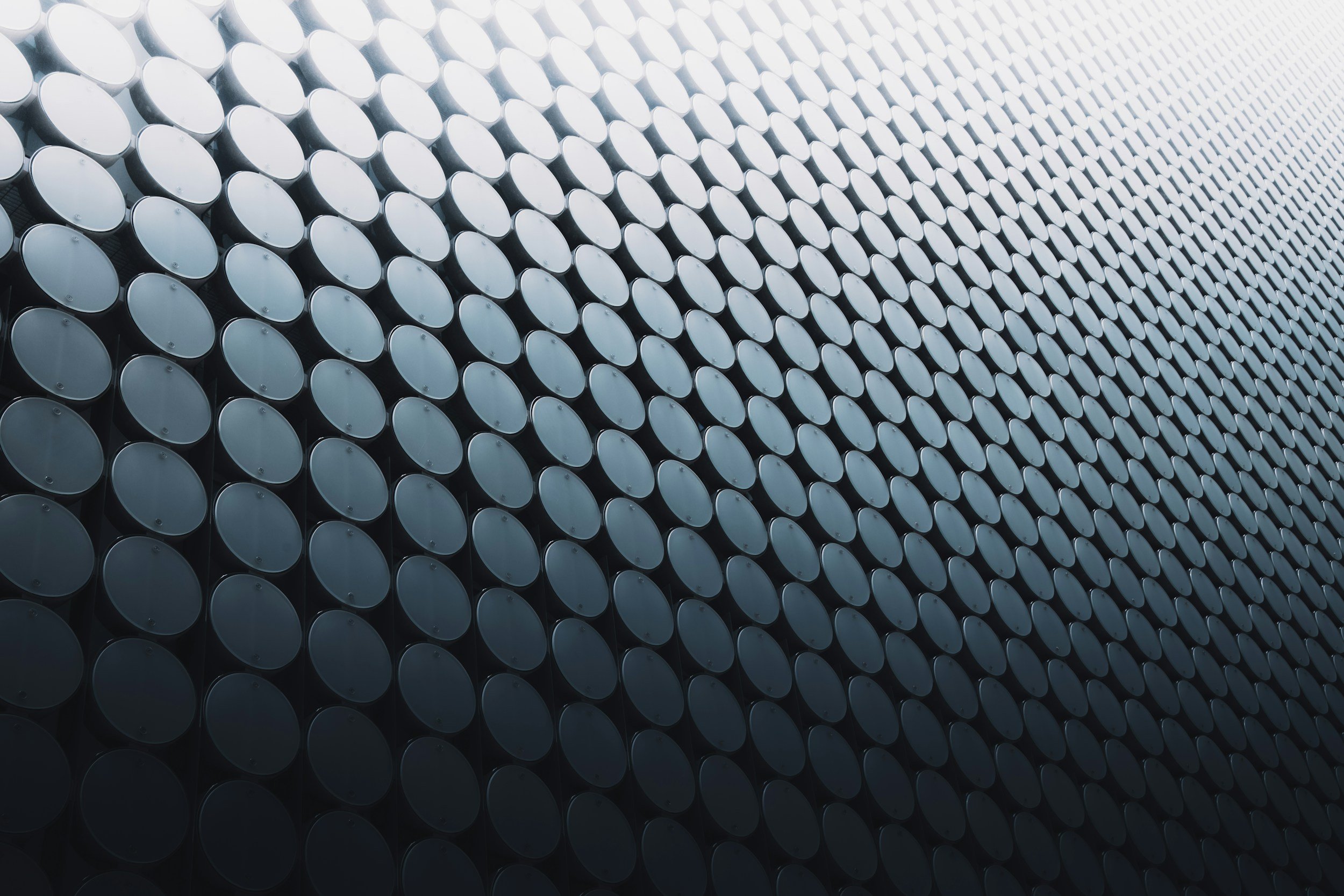 Close-up view of a modern building facade covered with numerous round, metallic panels arranged in a grid pattern, reflecting light.