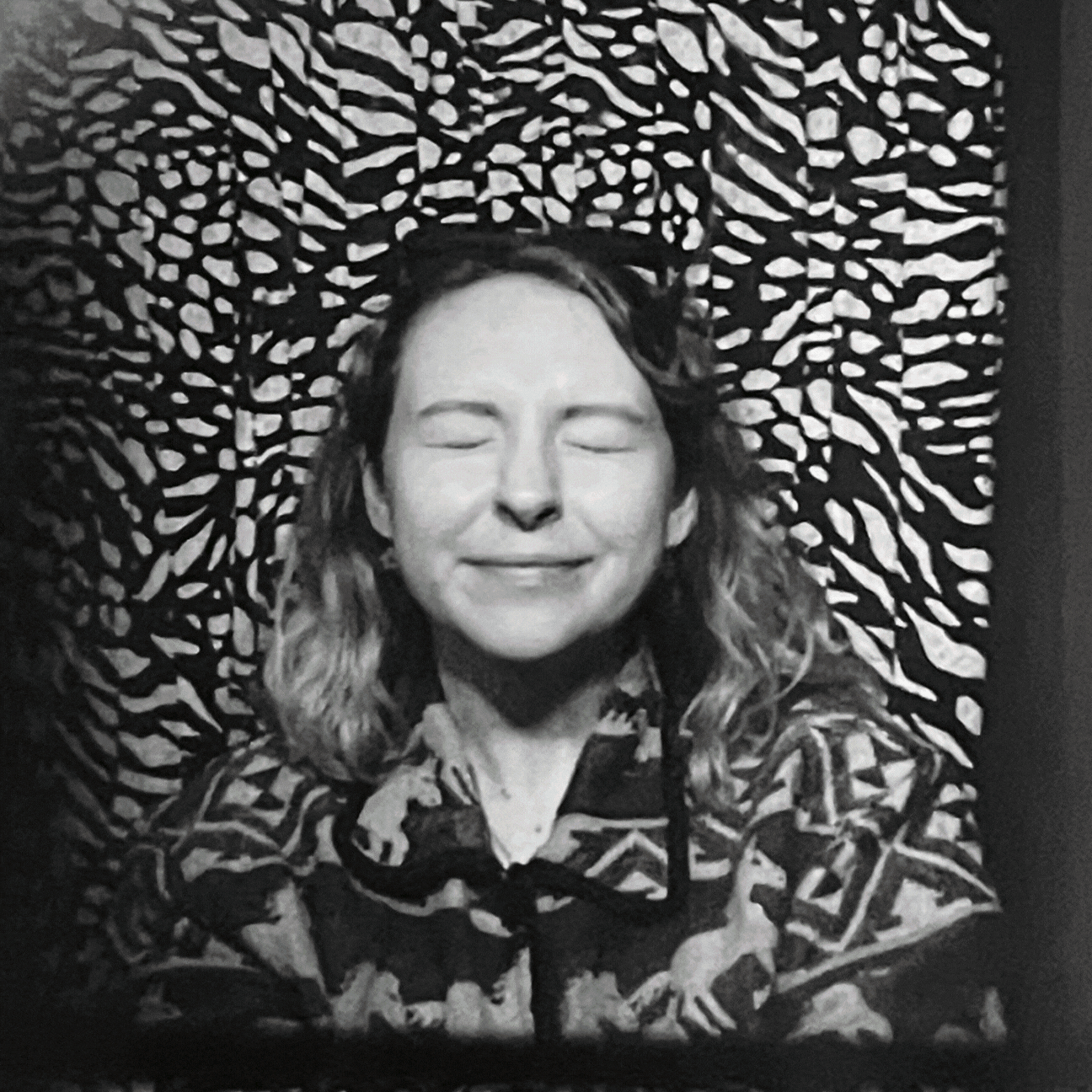 A woman with closed eyes and a peaceful smile lying on a zebra-print blanket.