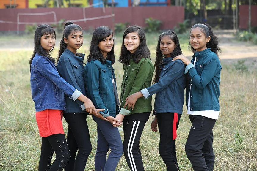 a group of girls pose together with linked hands