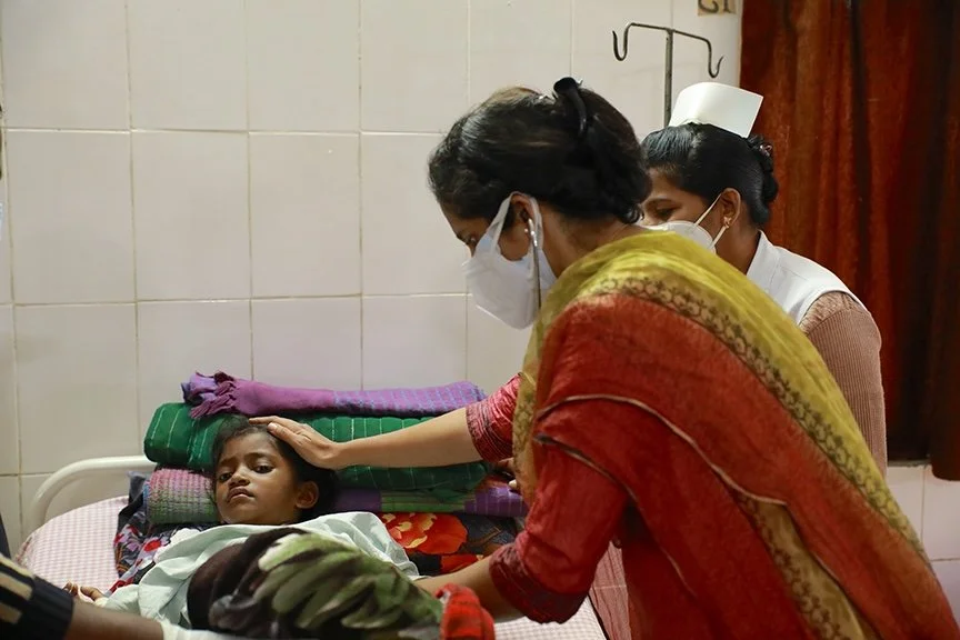 A doctor tends to a sick girl in bed