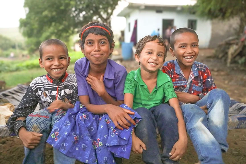 Four children sitting outside and smiling