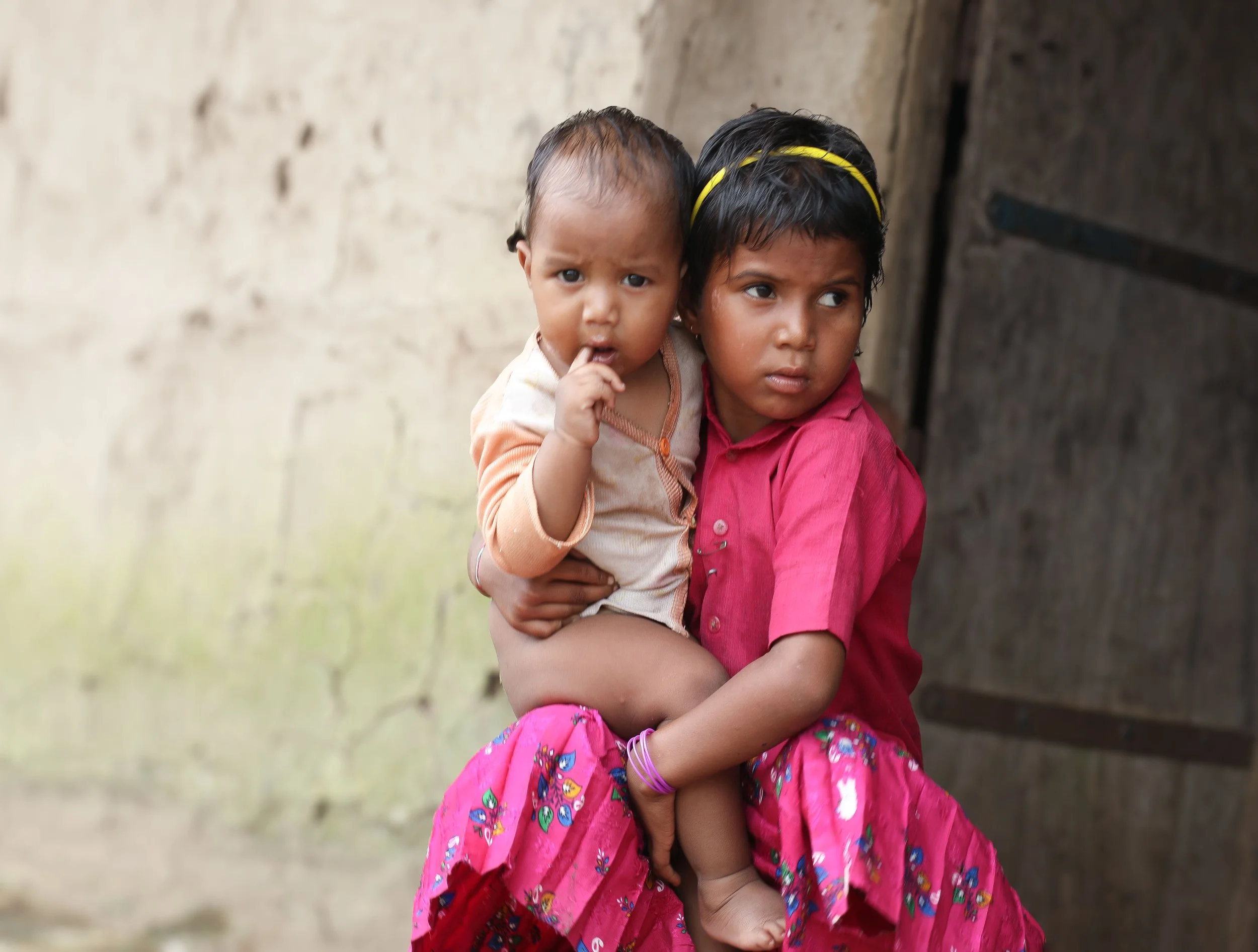 a young girl holds an infant in South Asia