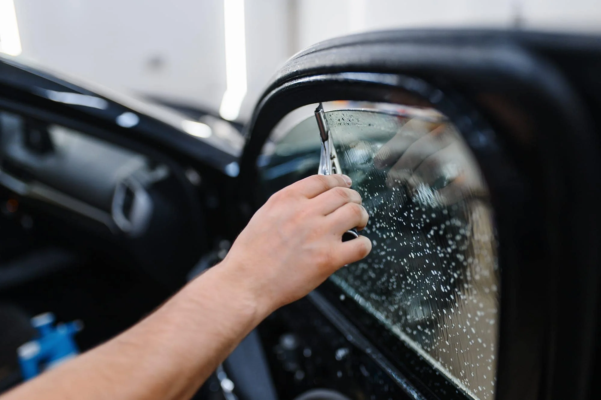 Person cleaning the window of a vehicle with a squeegee.