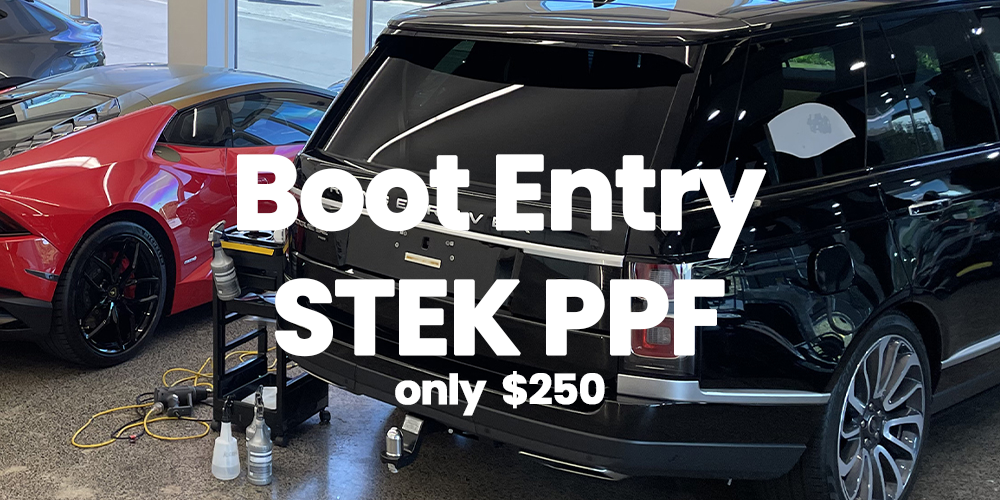 Inside a car dealership, there are two luxury vehicles: a red sports car and a black SUV. The SUV has a boot entry PPE sticker with price of $250 overlayed on the image.