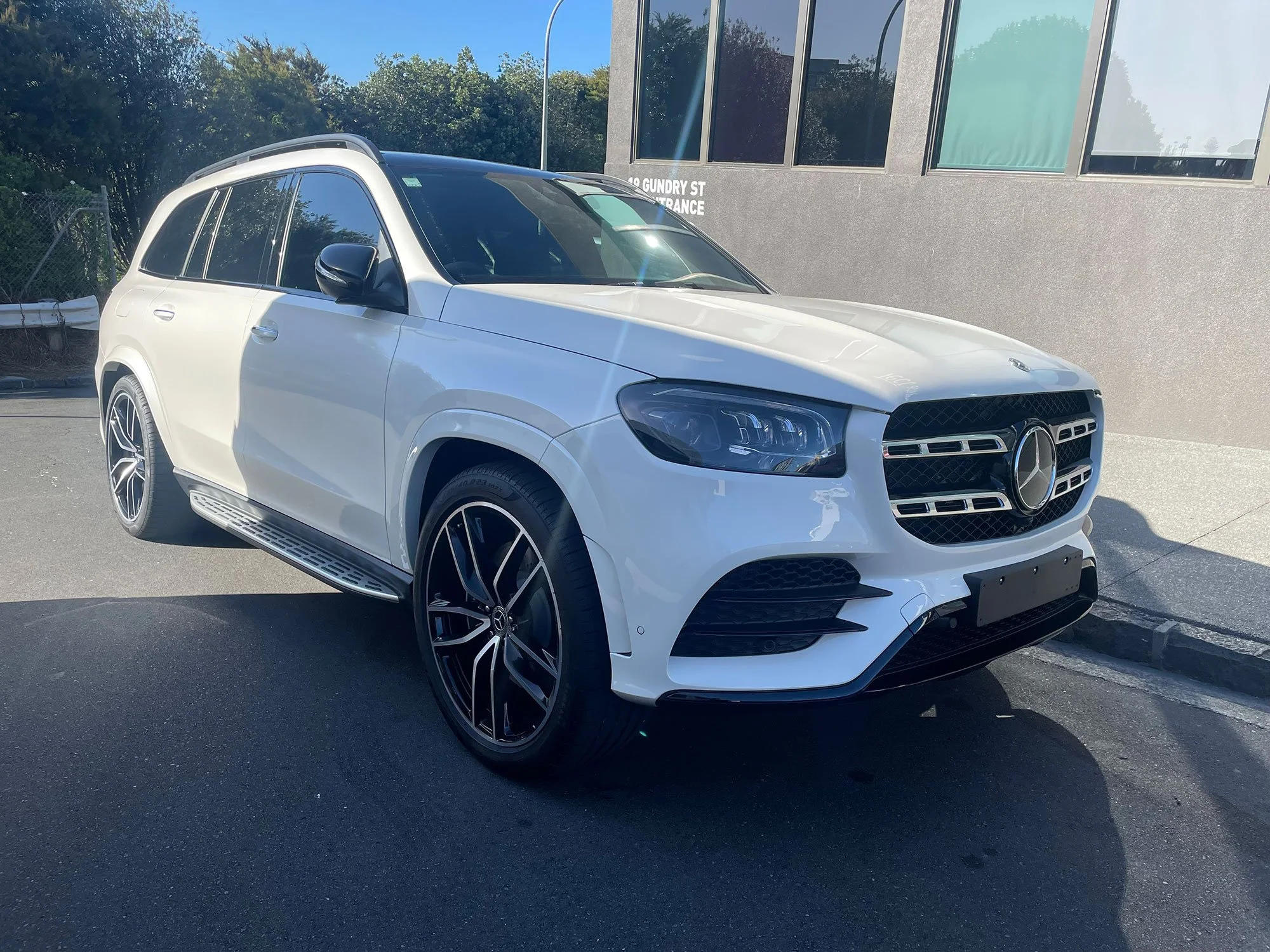 Front and side view of a white Mercedes-Benz SUV parked outdoors near a building.