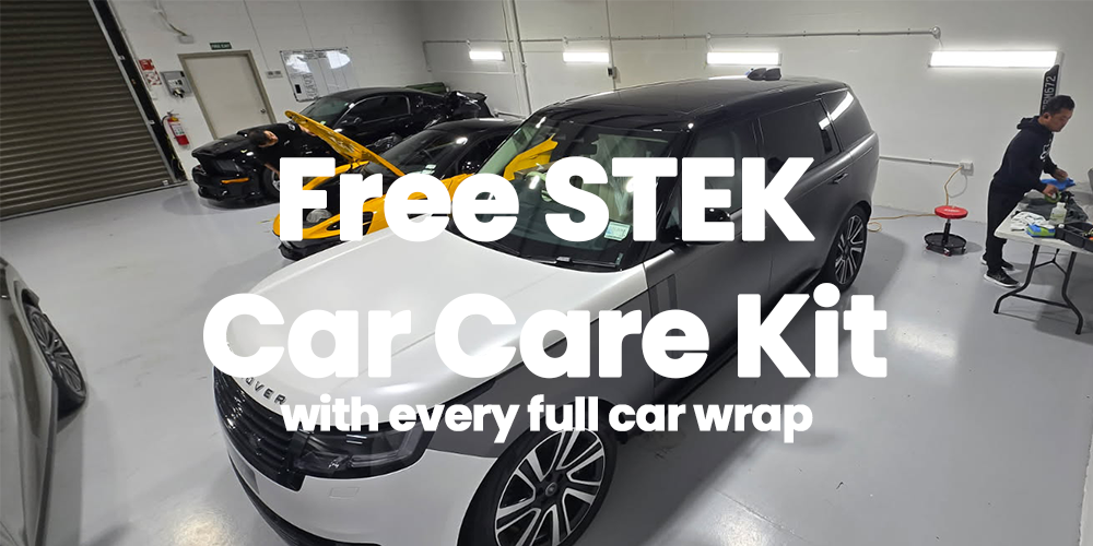 Indoor garage with multiple cars and a person working at a table.