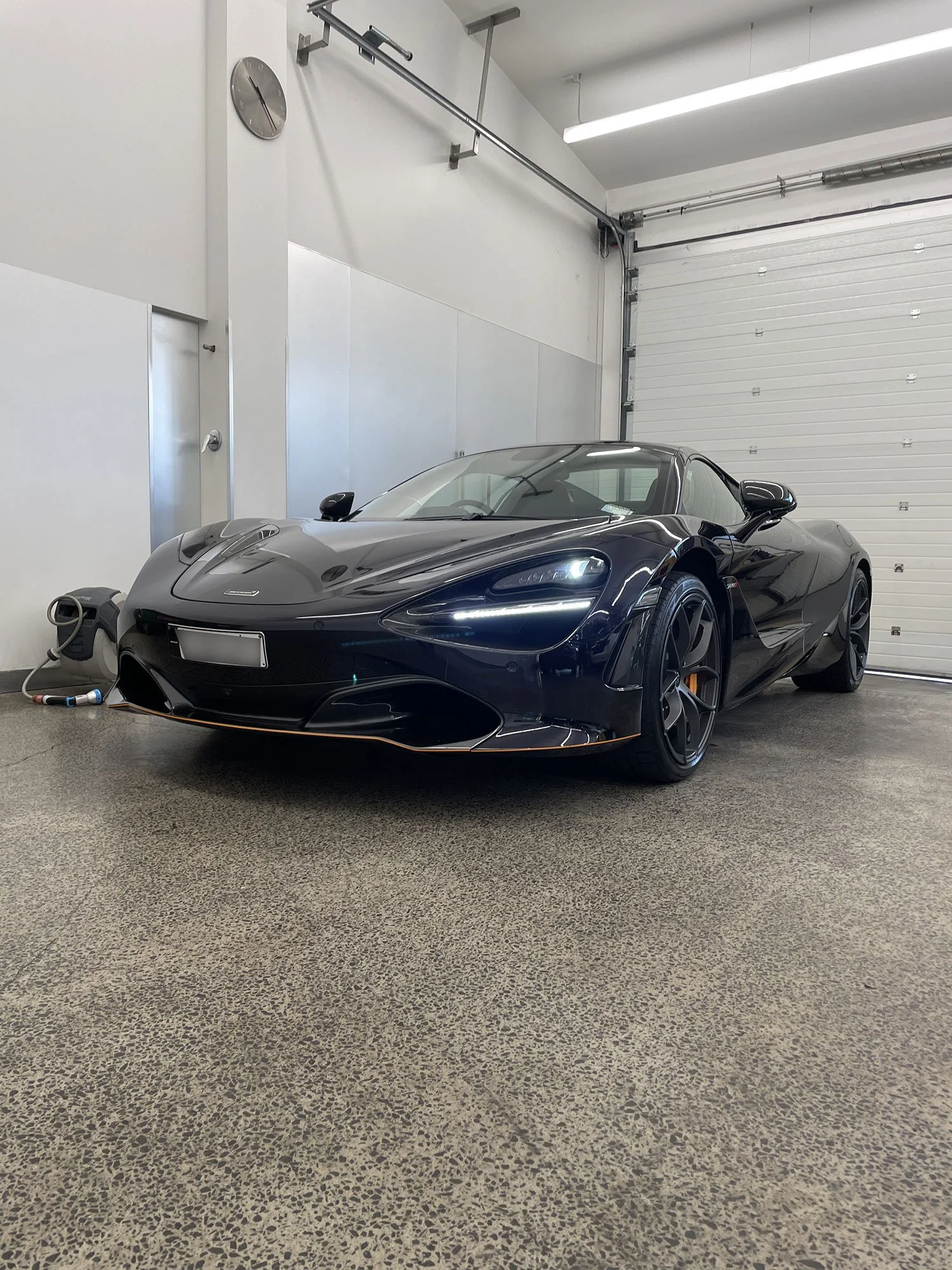 Black McLaren sports car inside a garage.