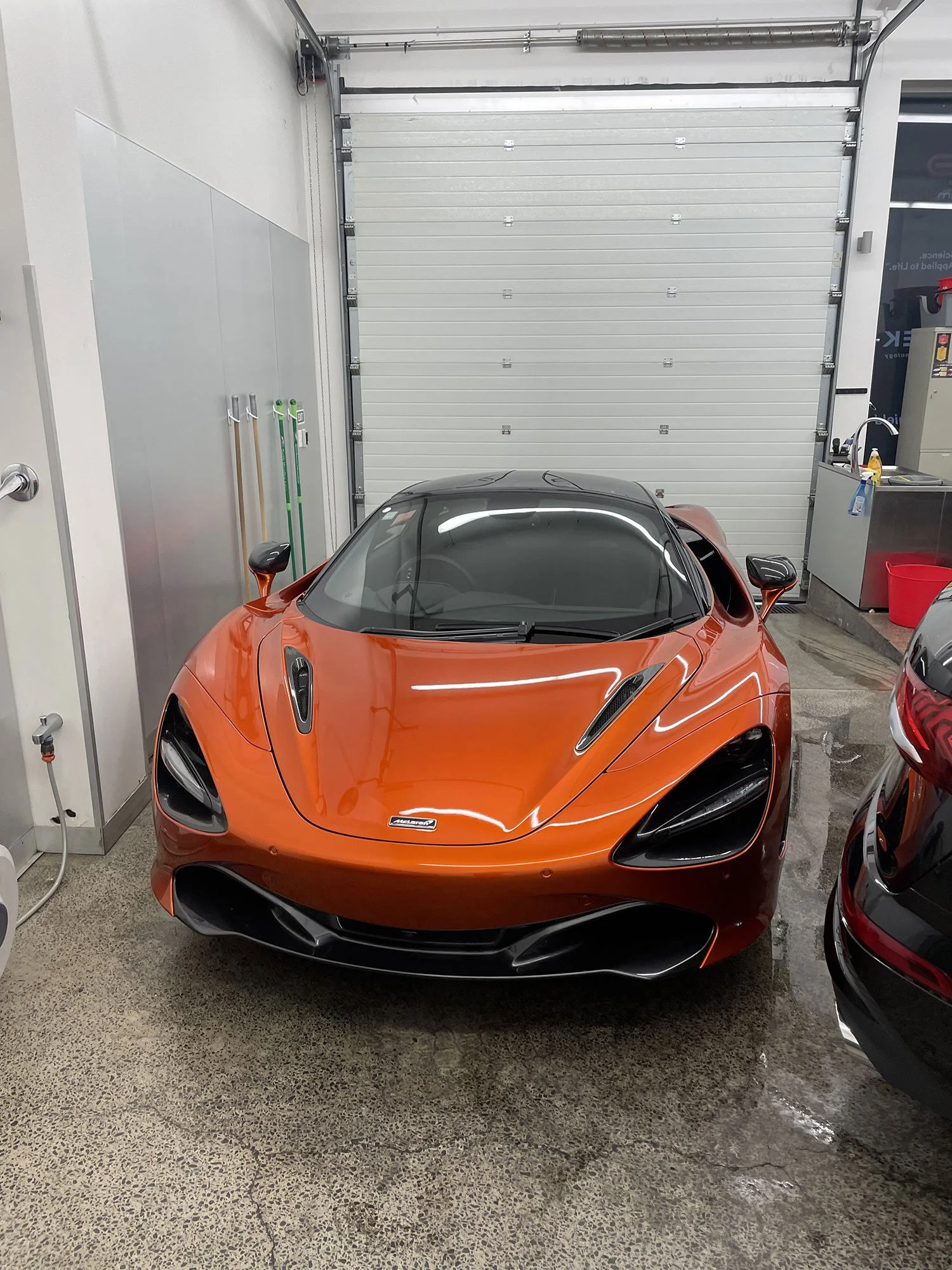 Orange sports car with black accents parked inside a garage.